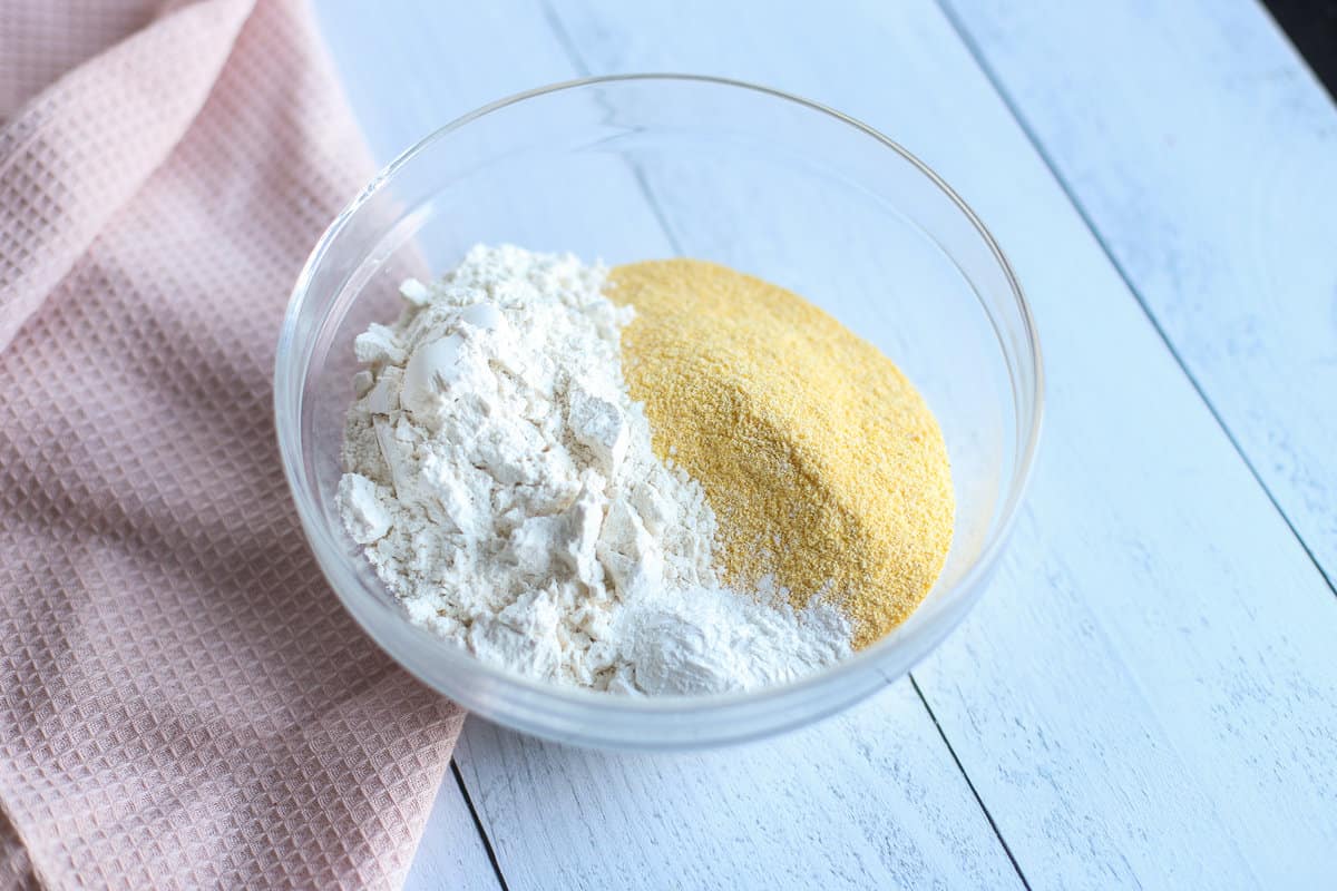 Dry ingredients for sweet potato corn bread in a glass mixing bowl.