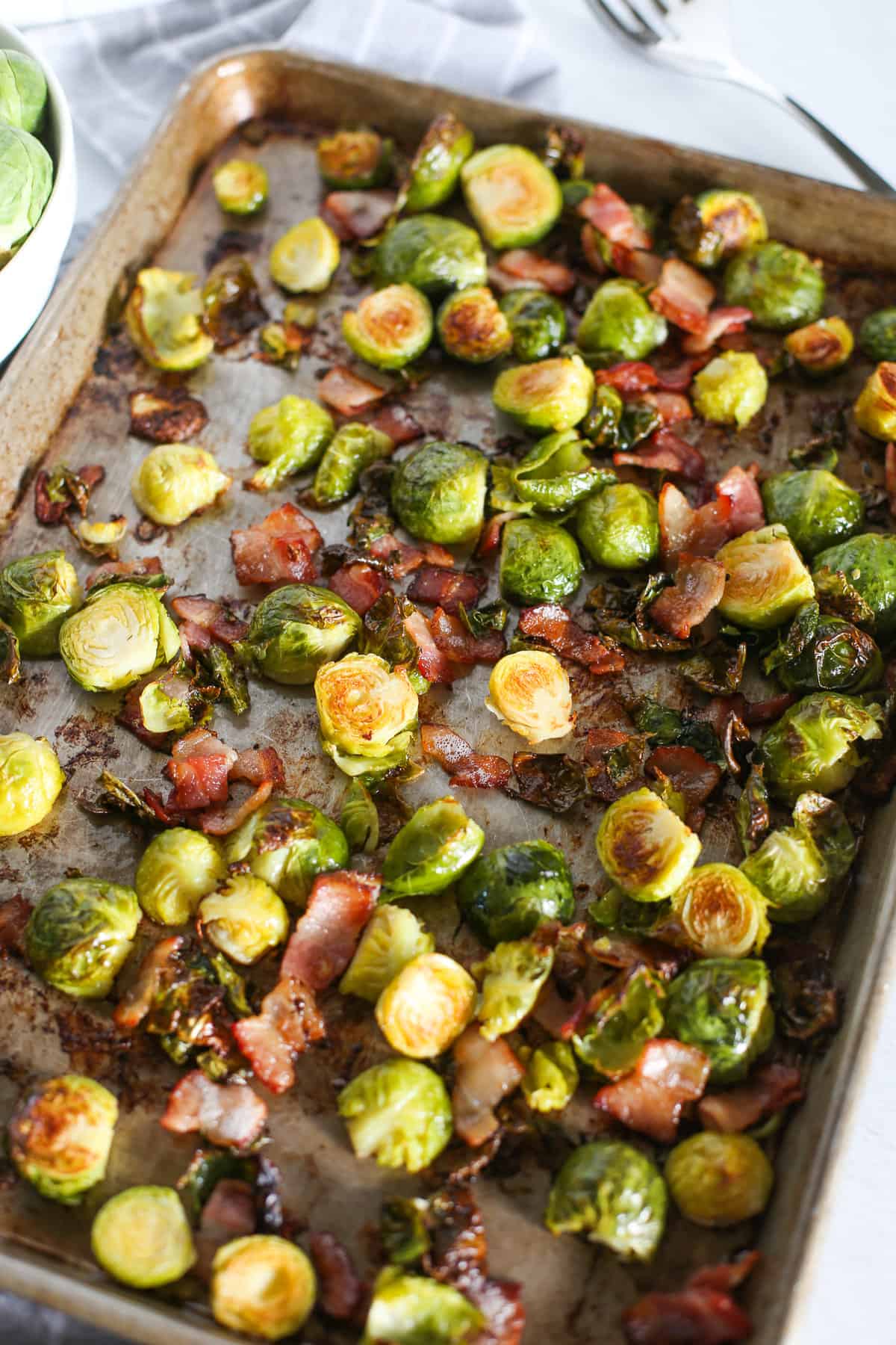 Roasted Brussels sprouts and bacon on a baking sheet.