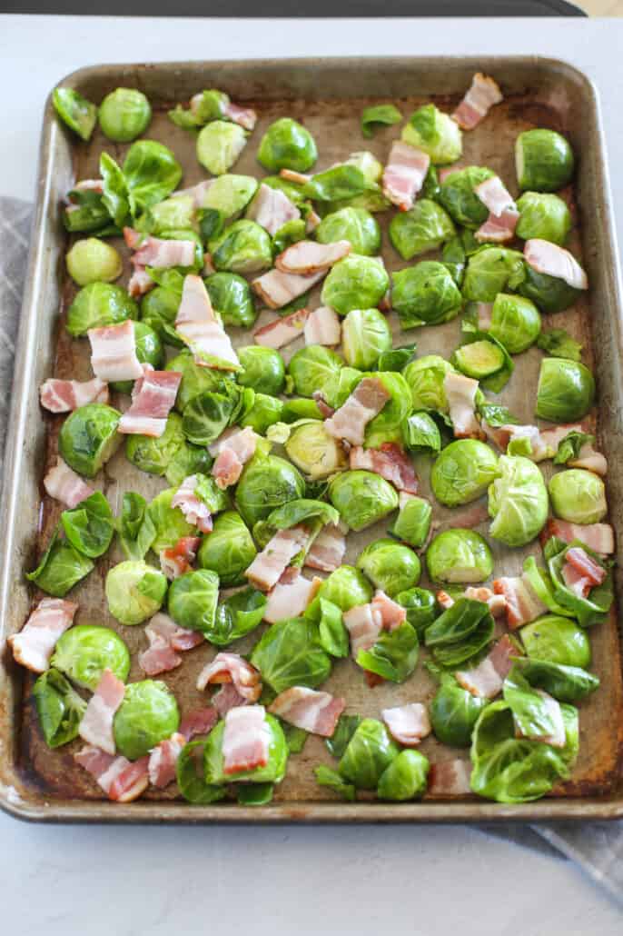 uncooked brussels sprouts and bacon on a baking sheet