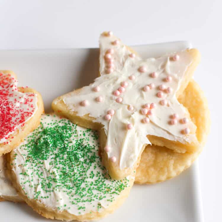 Decorated cream cheese sugar cookies on a square white plate.