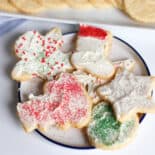 Cream cheese sugar cookies decorated and piled on a plate for serving.