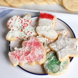 Cream cheese sugar cookies decorated and piled on a plate for serving.