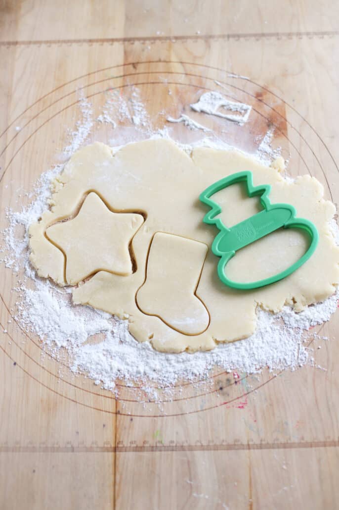 Sugar cookie dough rolled out with cookie cutters making shapes