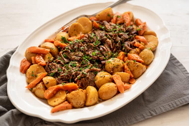 Pot roast on a platter with potatoes and carrots.