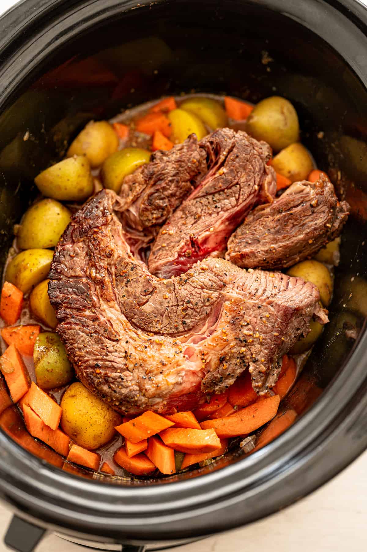 Crock pot pot roast over veggies in slow cooker.