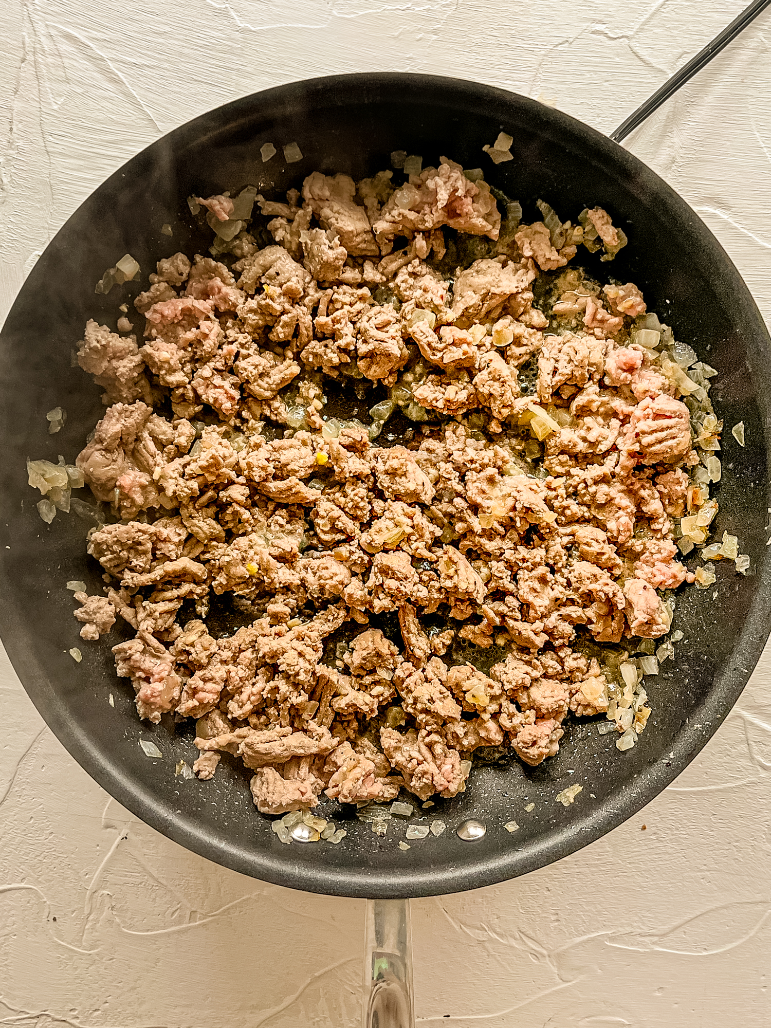 Ground beef browning in a skillet.