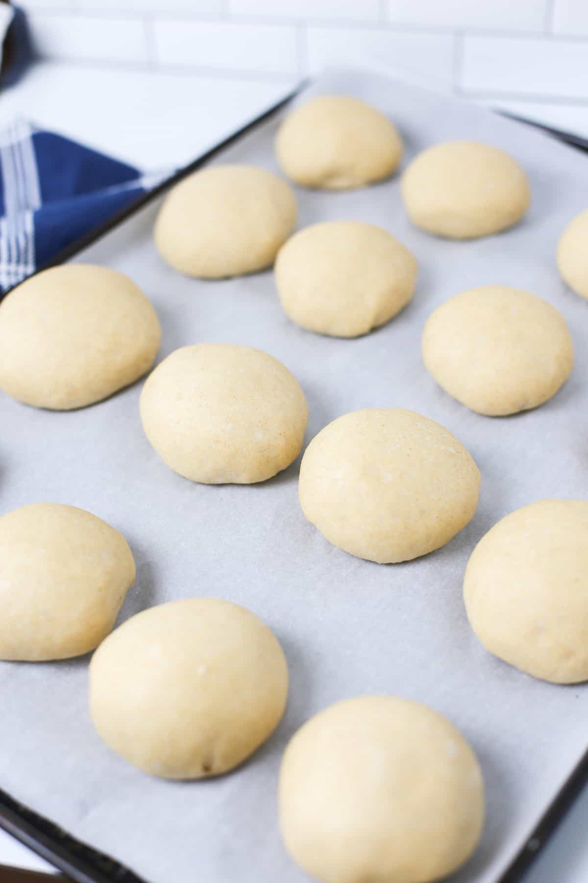 Dinner roll dough on a baking sheet after rising for 1 hour.