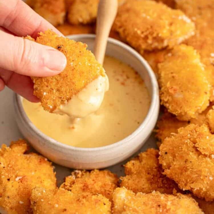 Chicken nuggets dipped in honey mustard dipping sauce.