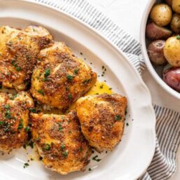 Italian Baked Chicken Thighs on a white platter.