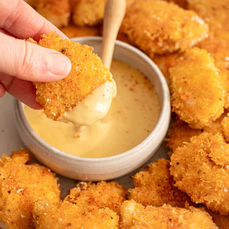 Chicken nuggets dipped in honey mustard dipping sauce.