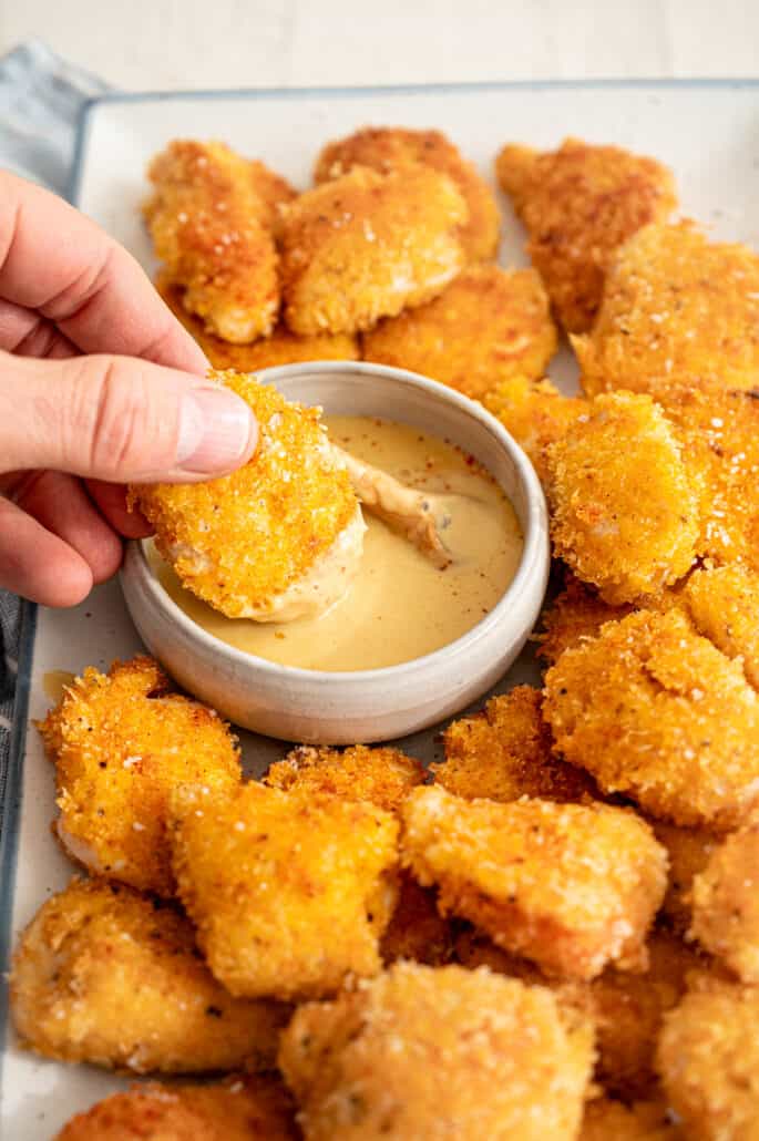 hand dipping a chicken nugget in honey mustard dipping sauce