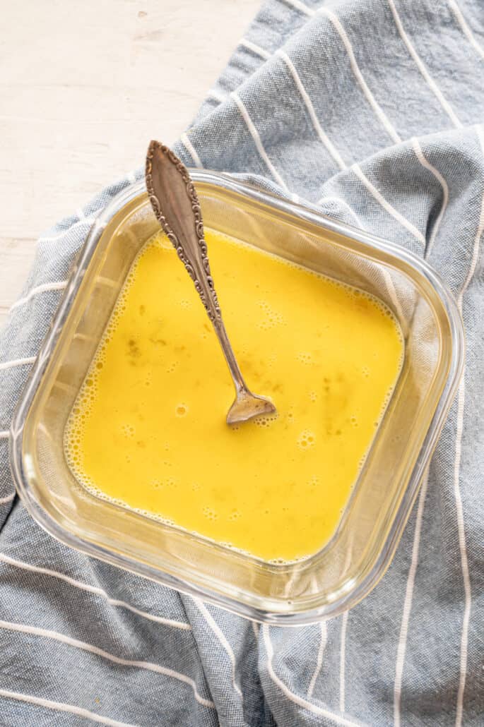 Egg wash in a small bowl with a fork.