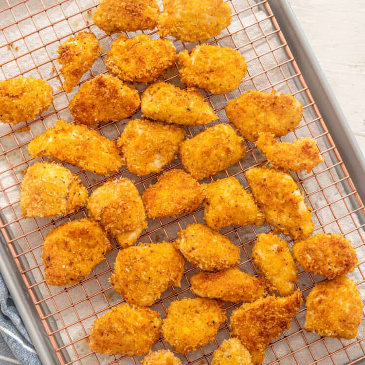 Homemade chicken nuggets on a cooling rack on a baking sheet lined with parchment paper.