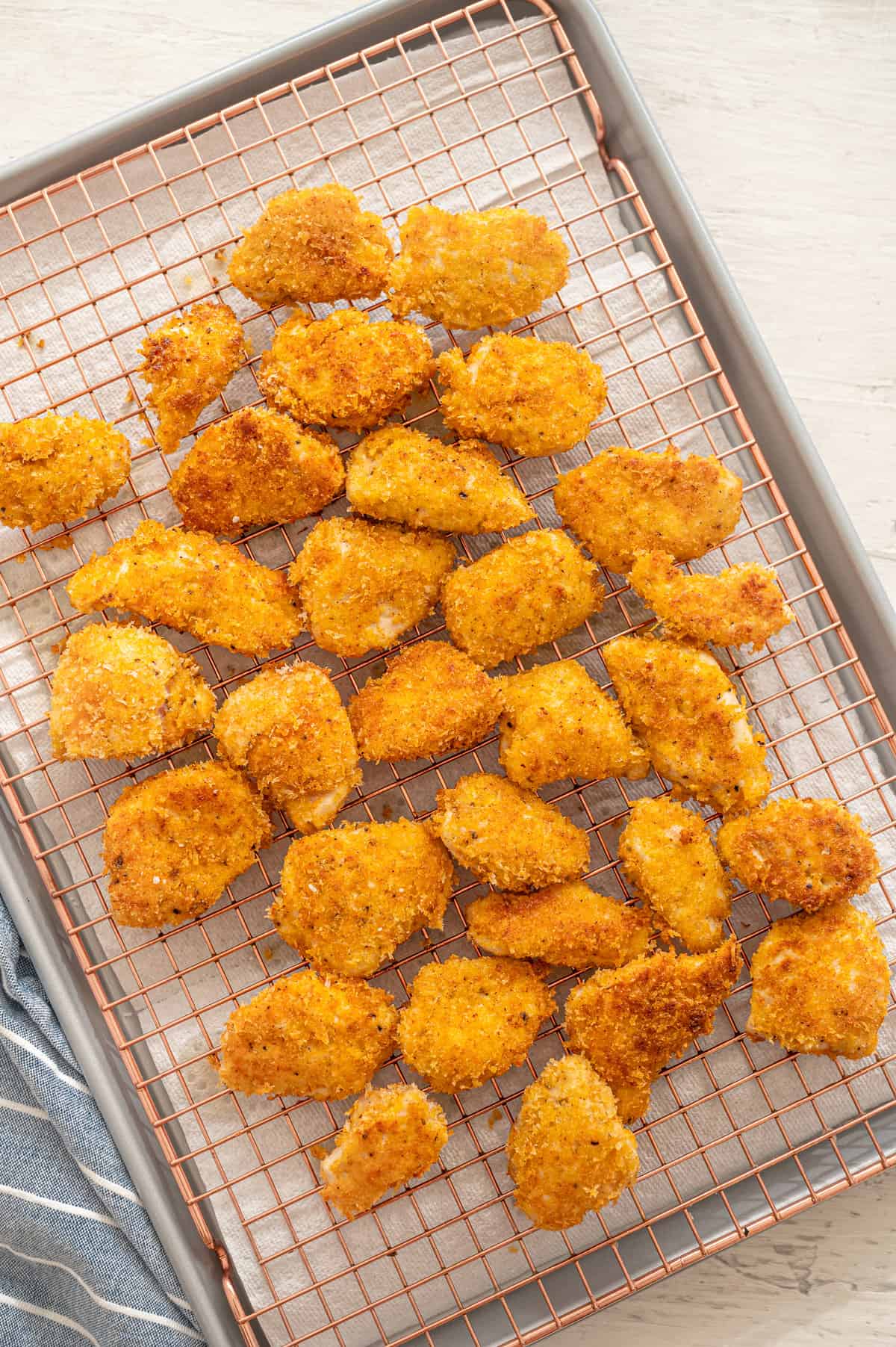 Homemade chicken nuggets on a cooking rack on top of baking sheet.