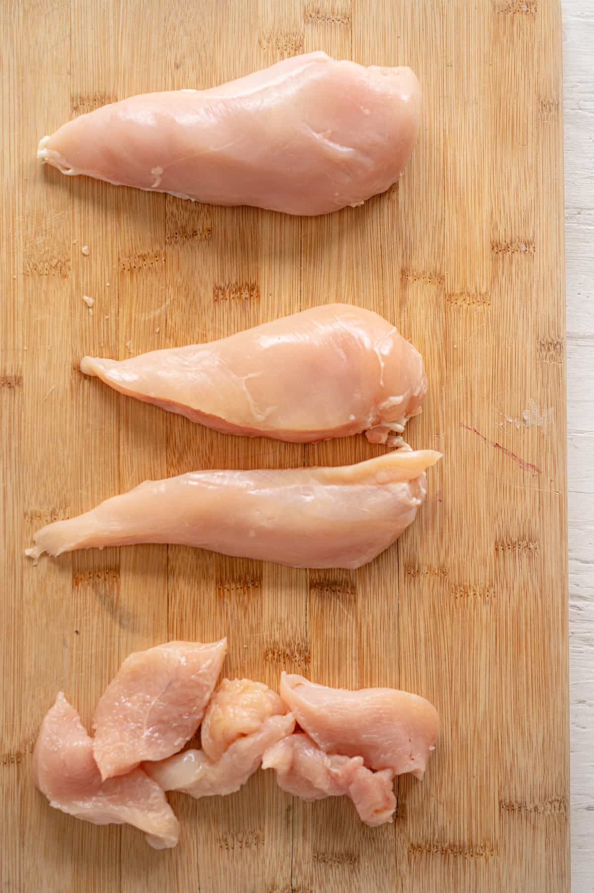 Cut up chicken breasts on cutting board.
