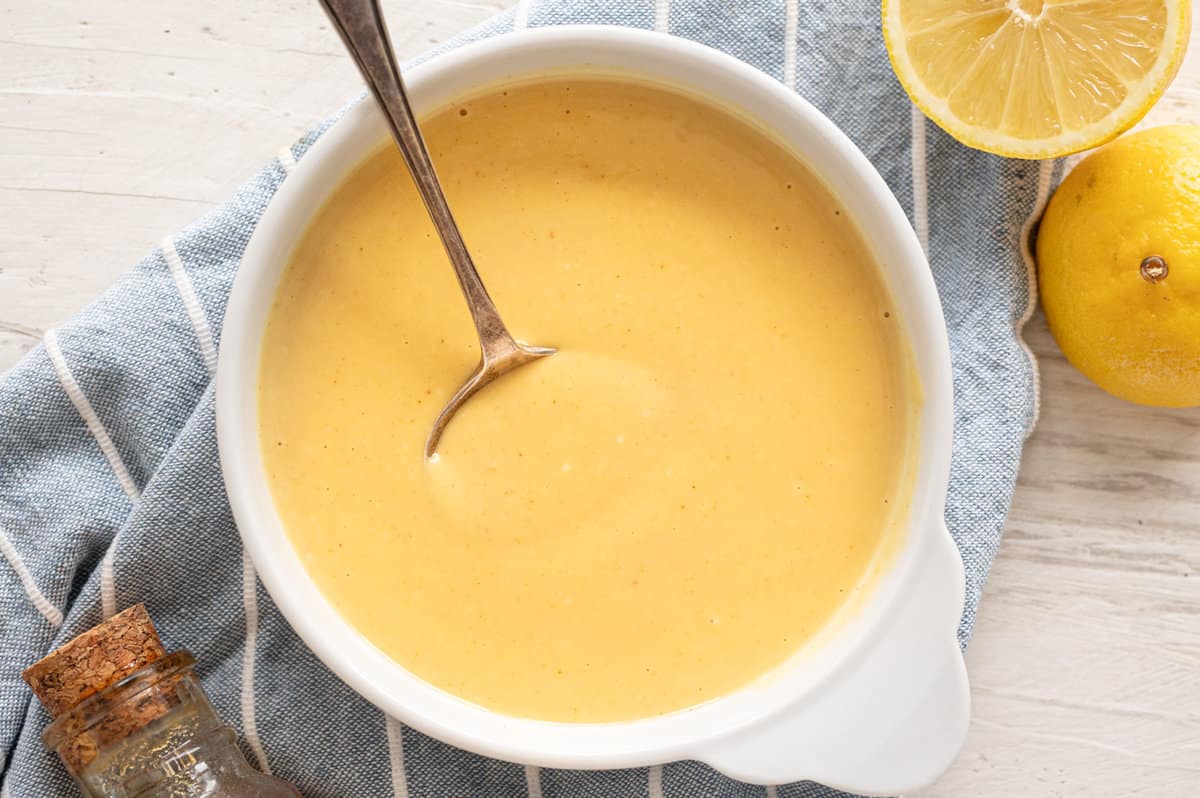 Honey mustard dipping sauce in a bowl with lemons on the side.