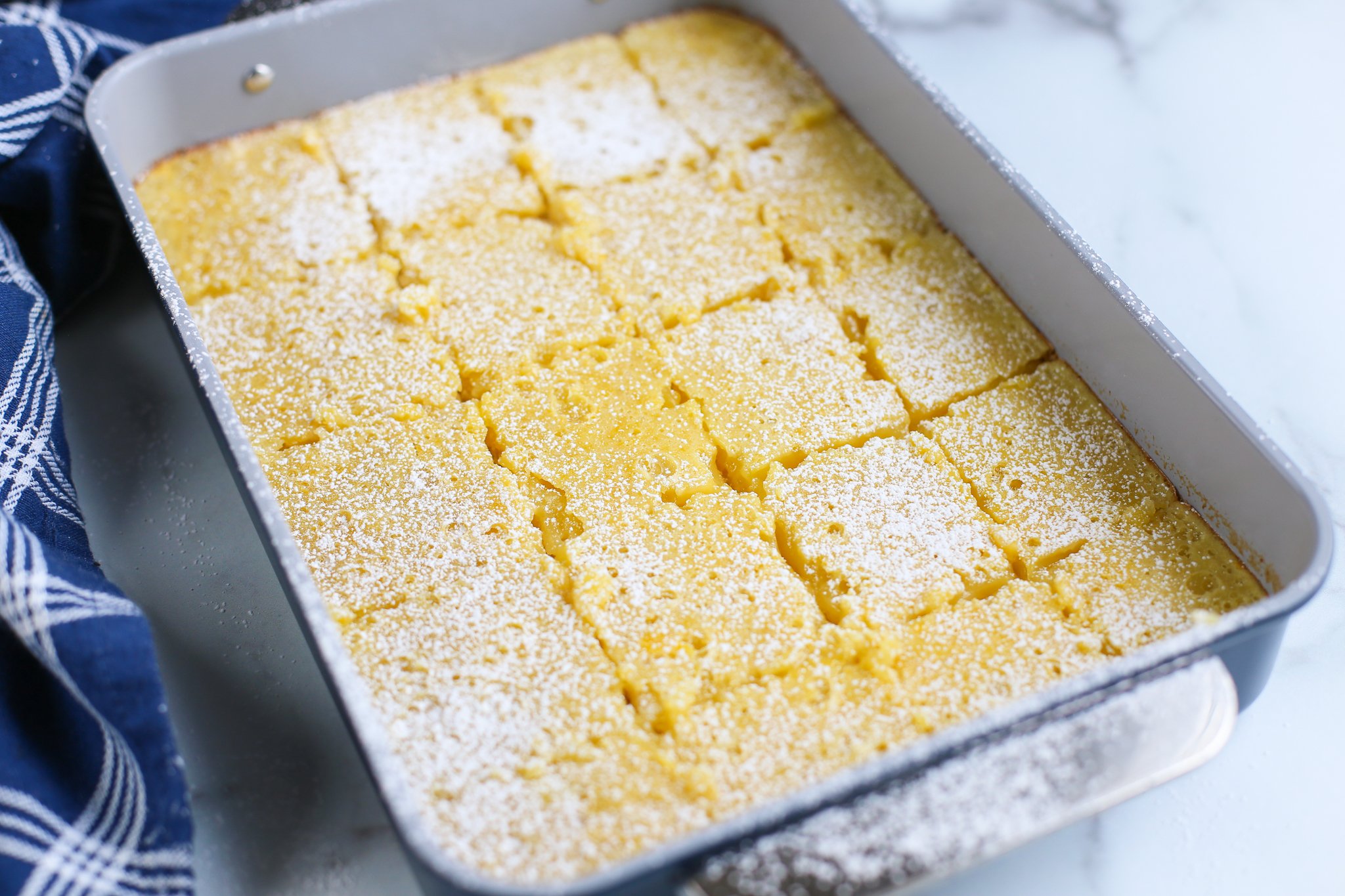 Baked lemon bars sprinkled with powdered sugar and cut in 12 squares.