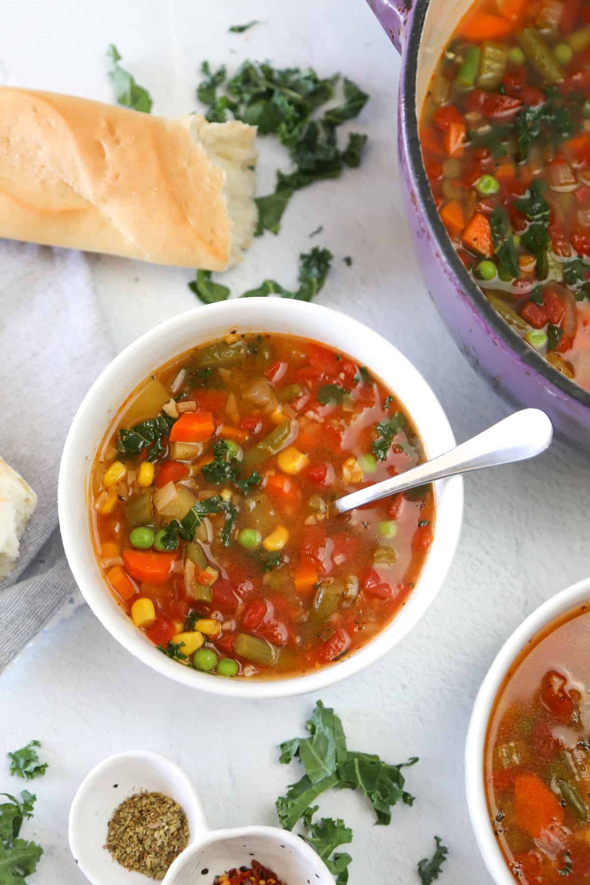 Easy vegetable soup in white bowl with french bread next to it.