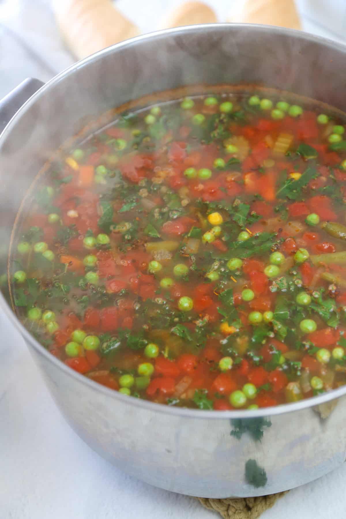 Peas, and kale being stirred in to veggie soup.
