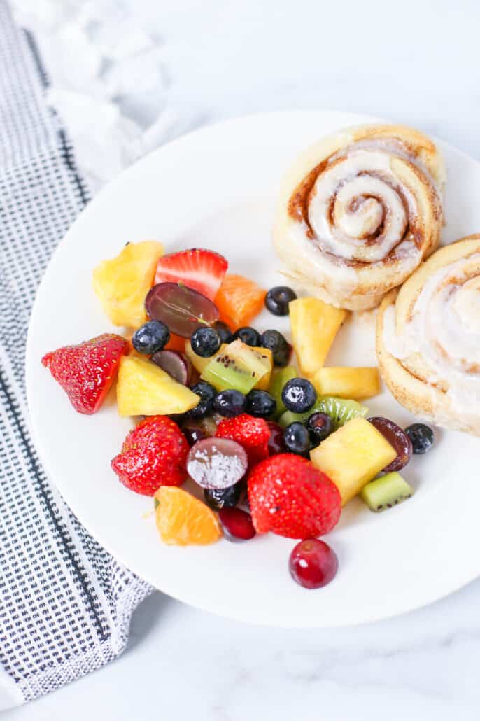 fruit salad on a plate with cinnamon rolls