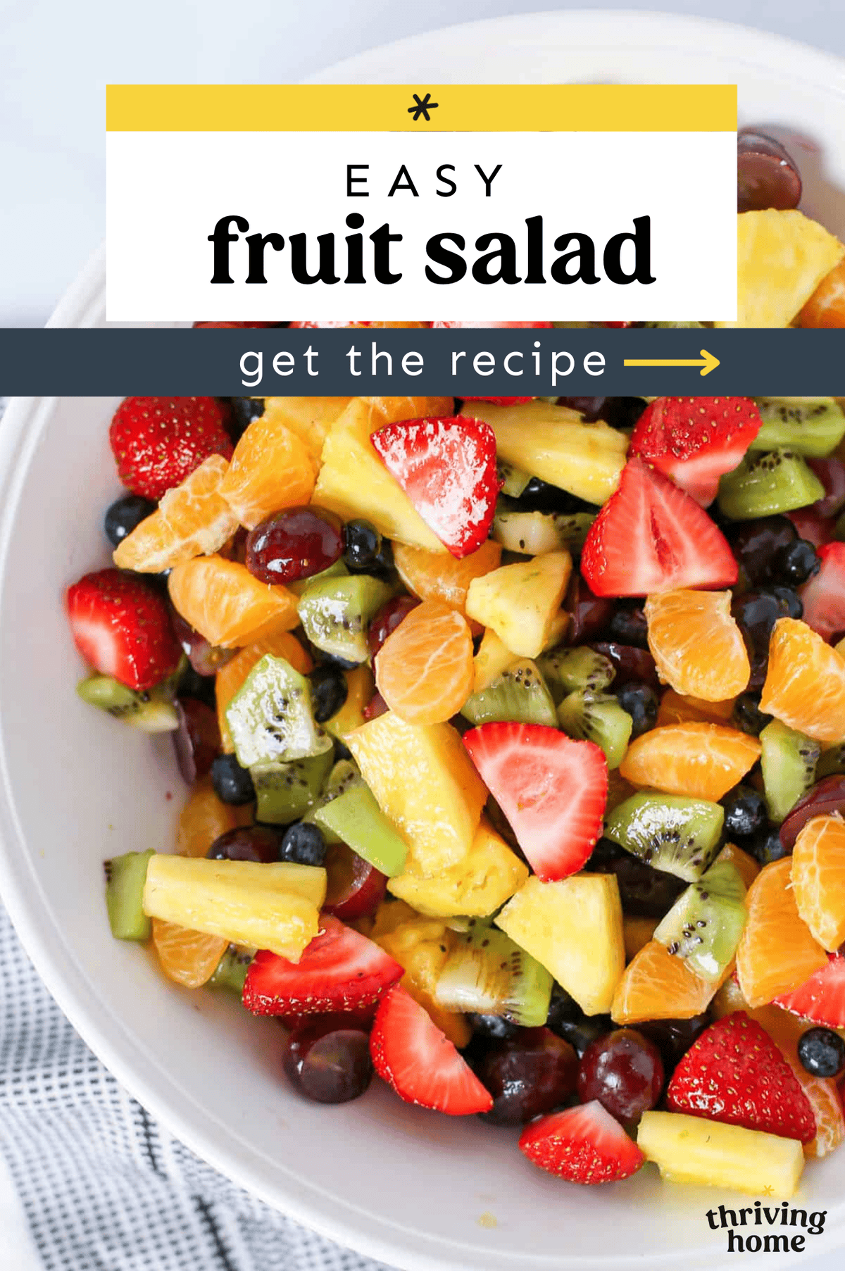 White bowl with fruit salad of strawberries, blueberries, pineapple, kiwi, and grapes.