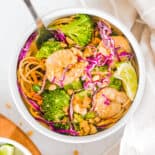 A shrimp curry bowl complete with chopped peanuts and a lime wedge on top.