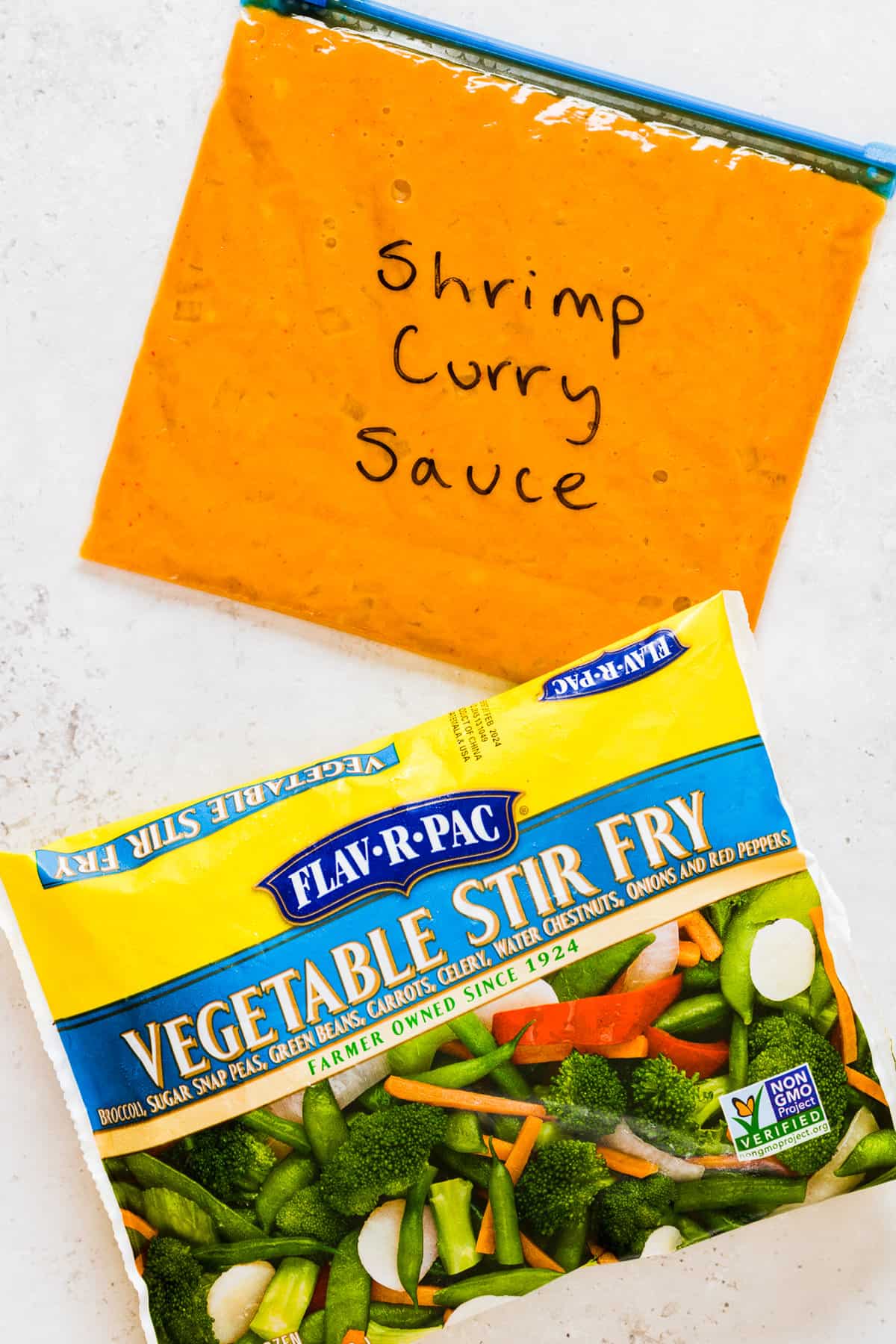 Shrimp curry sauce in freezer bag and a frozen bag of vegetable stir fry.