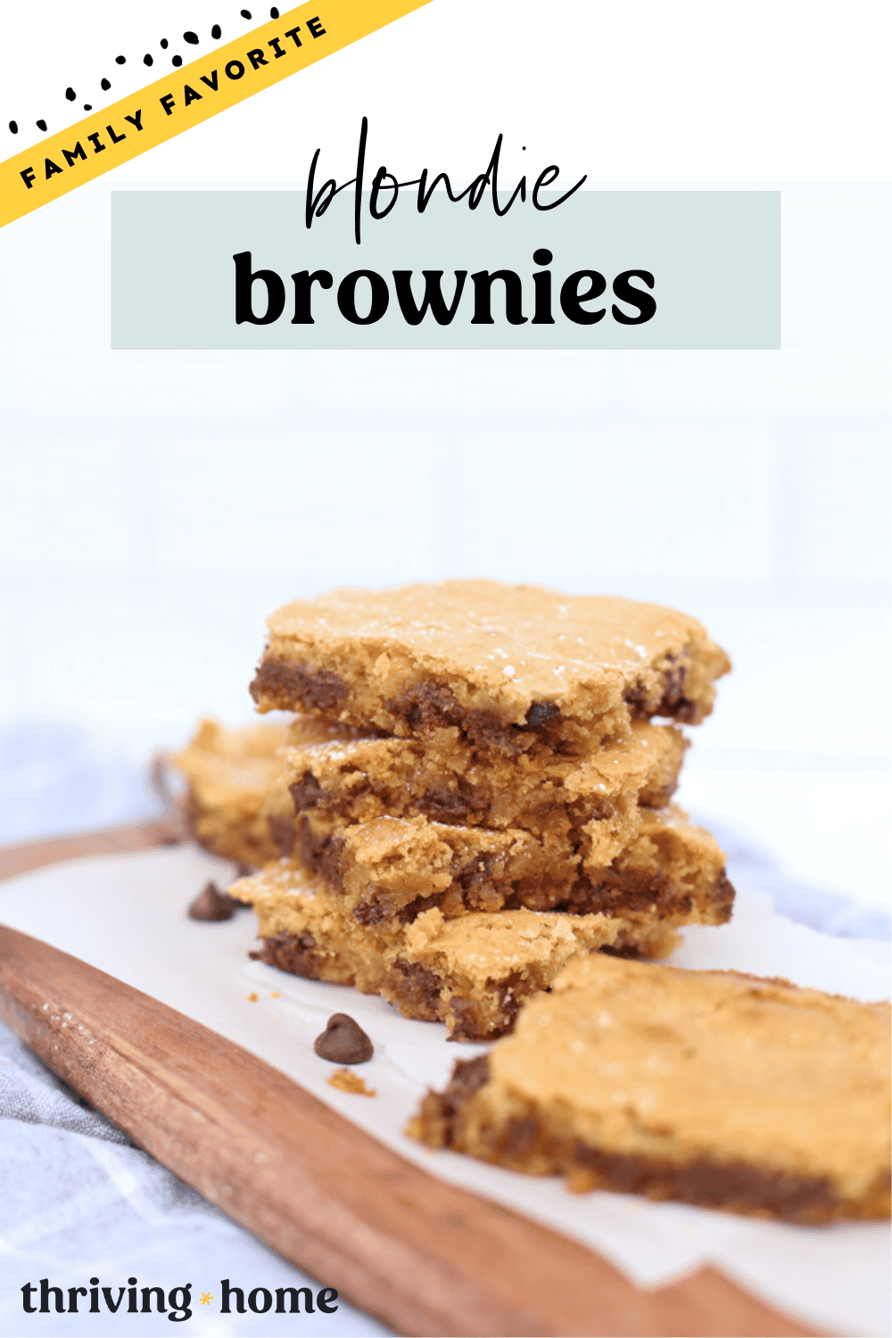 Blondie brownies stacked up on a parchment-lined cutting board.