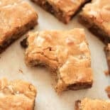 Blondie brownies cut in squares with one having a bite out of it.