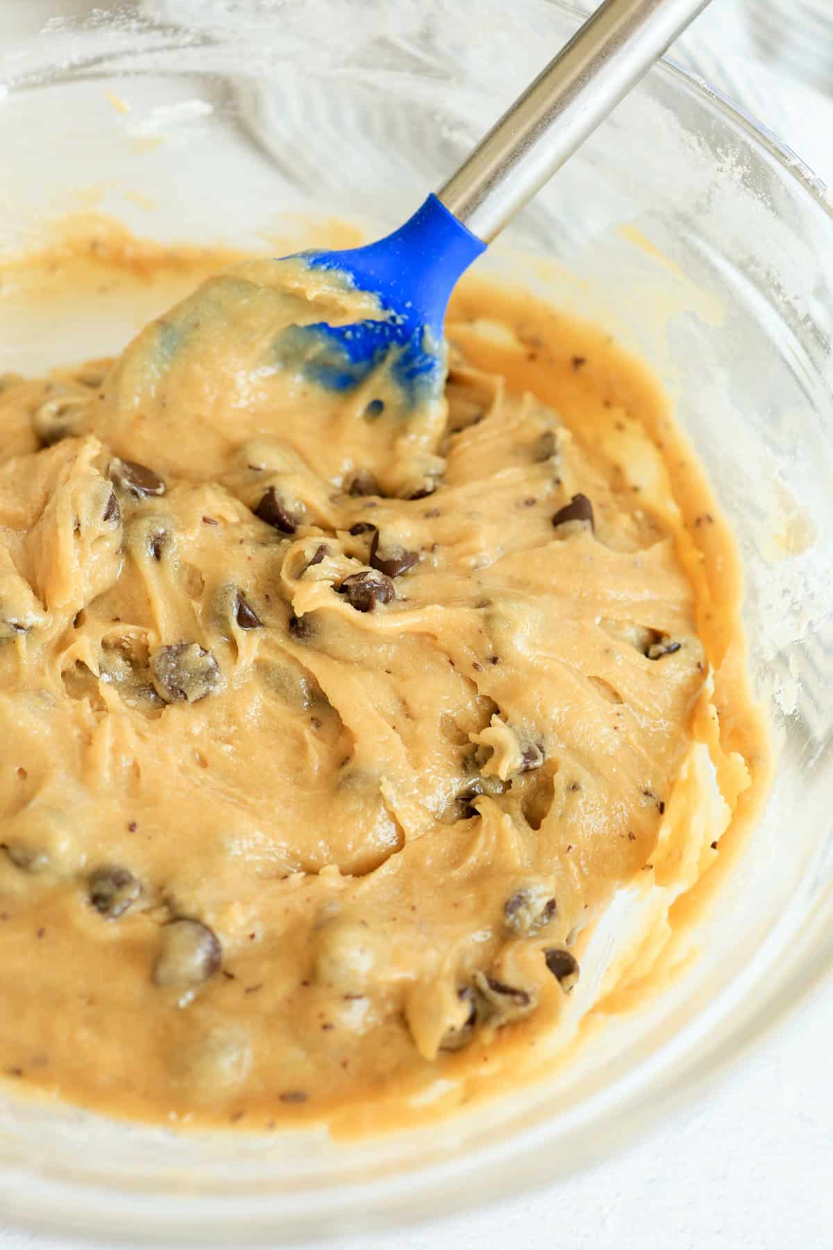 A spoon stirring chocolate chips into cookie dough.