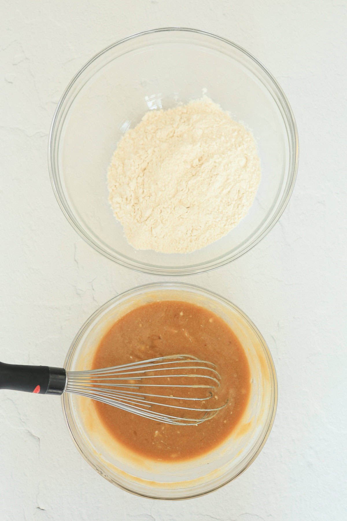 Two mixing bowls, one with wet ingredients and one with dry ingredients for blondie brownies.