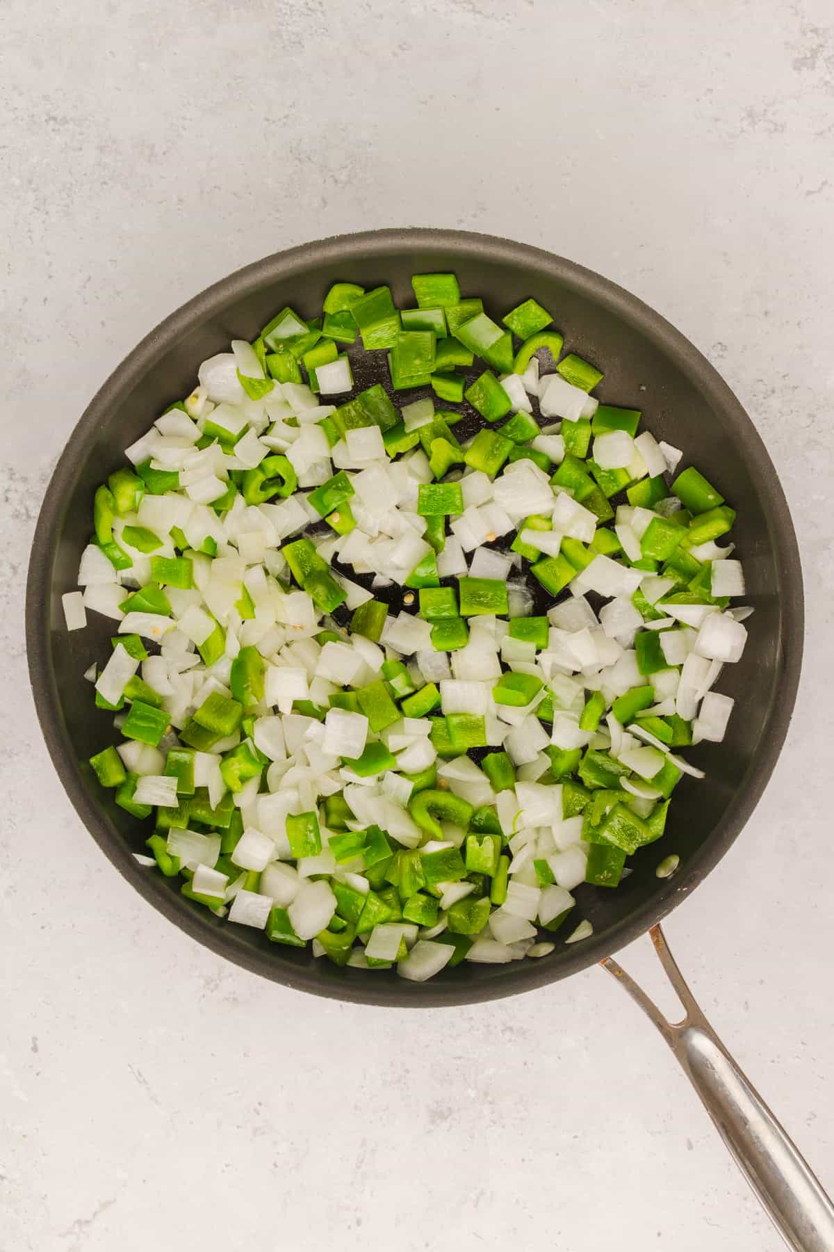 Green peppers and onions sauteing in a skillet.
