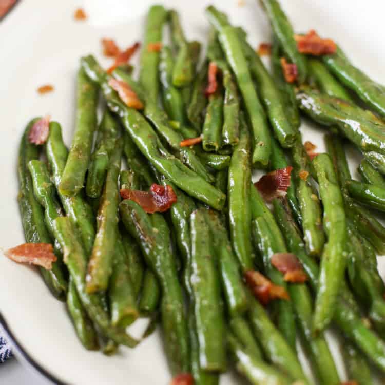 Garlic Green Beans on a white serving platter with bacon crumbled on top.