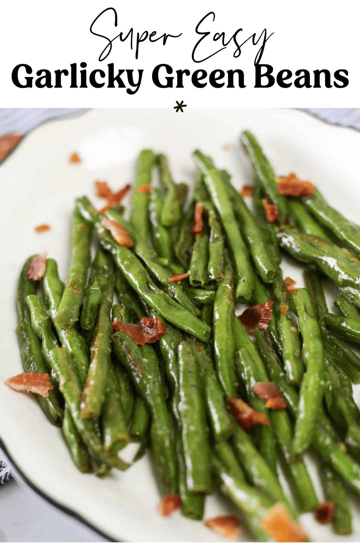Cooked green beans with chopped bacon on a white platter.