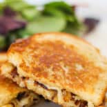 Gourmet grilled cheese sandwich with sauteed onions falling out.