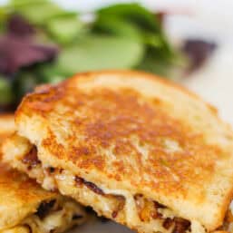Gourmet grilled cheese sandwich with sauteed onions falling out.