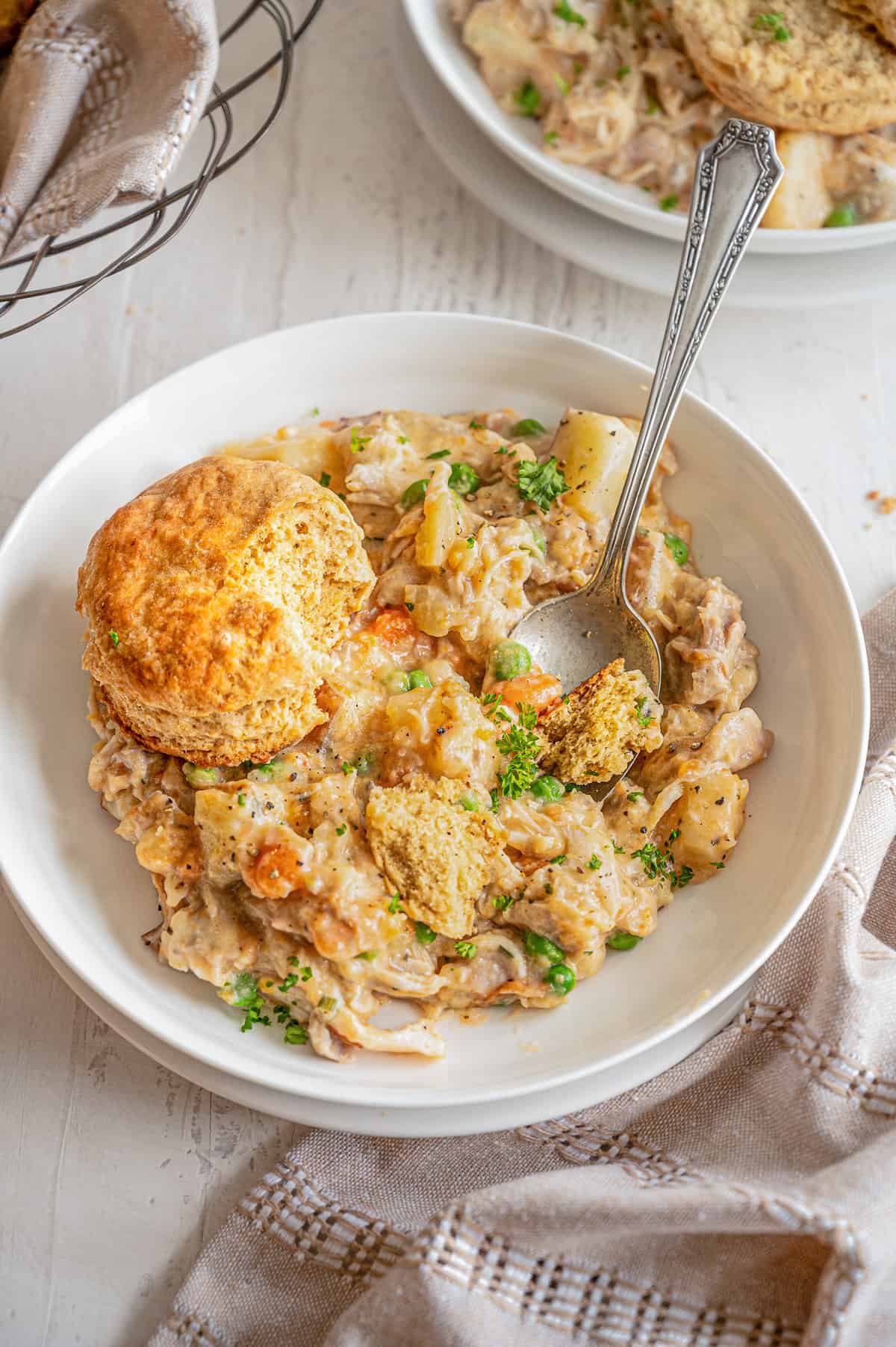 Chicken pot pie mixture in a bowl with a whole wheat biscuit on top.