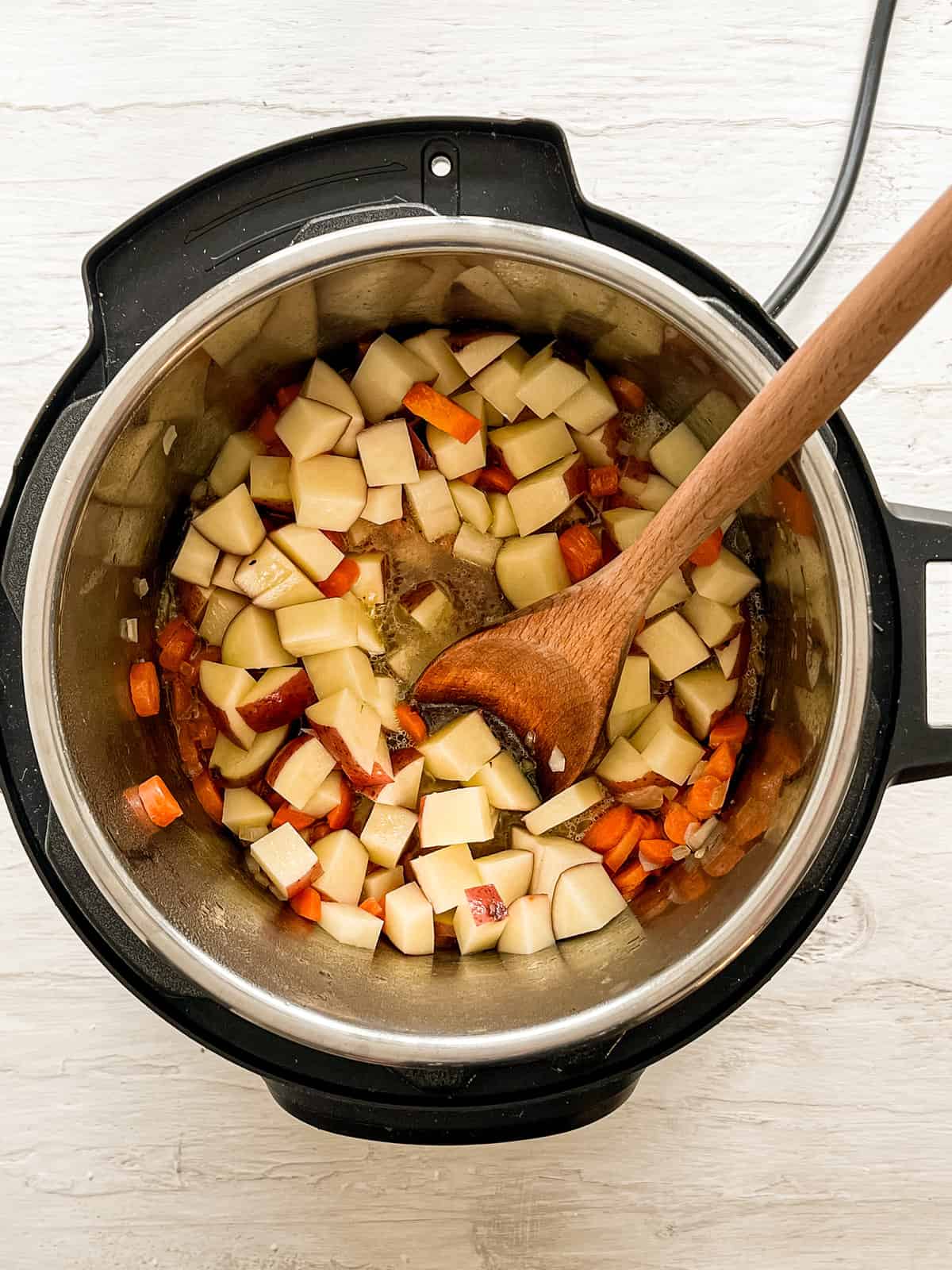 red potatoes, carrots, and onions being sauteed in Instant Pot