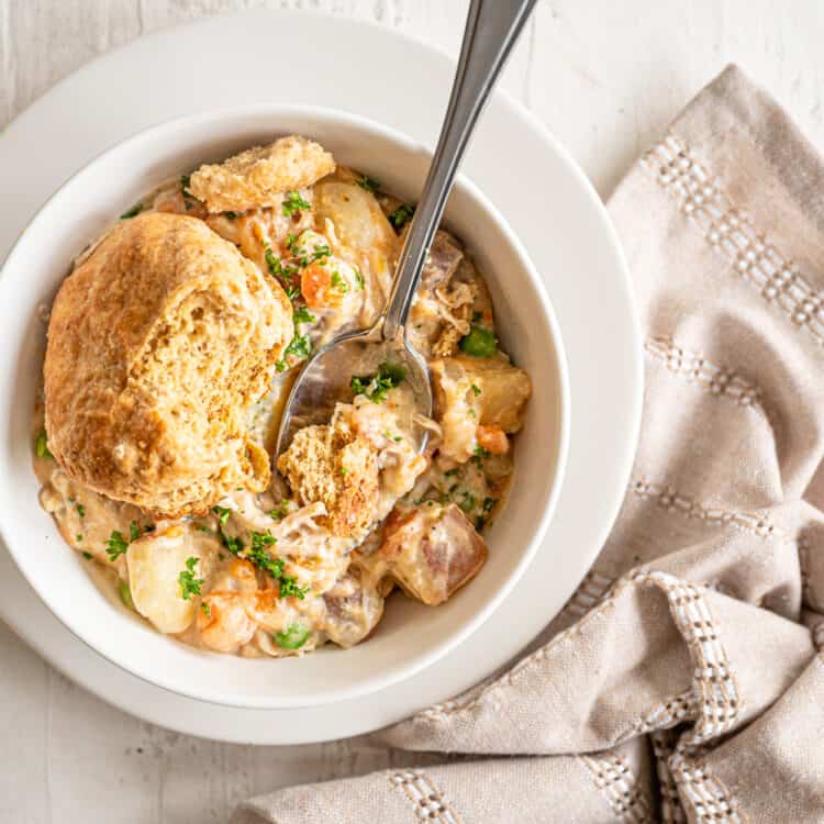 Chicken pot pie filling in a bowl with a biscuit on top.