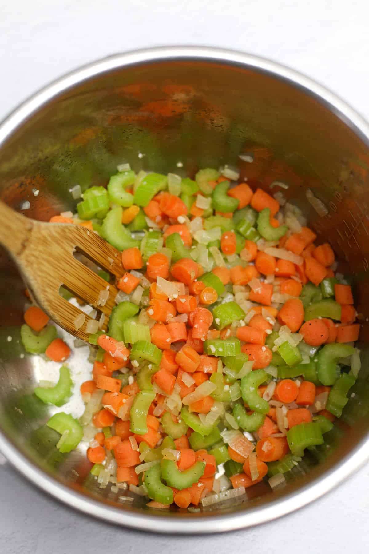 Chopped celery, onion, and carrots sauteed in an instant pot bowl.