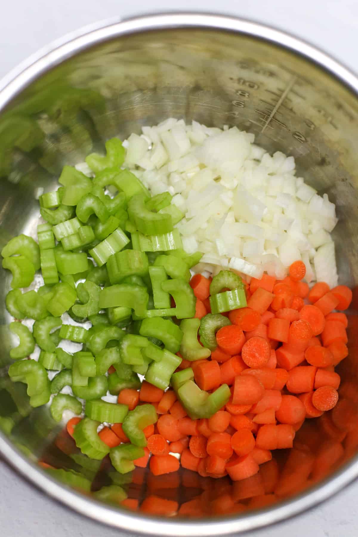 Chopped celery, onion, and carrot in an instant pot bowl.