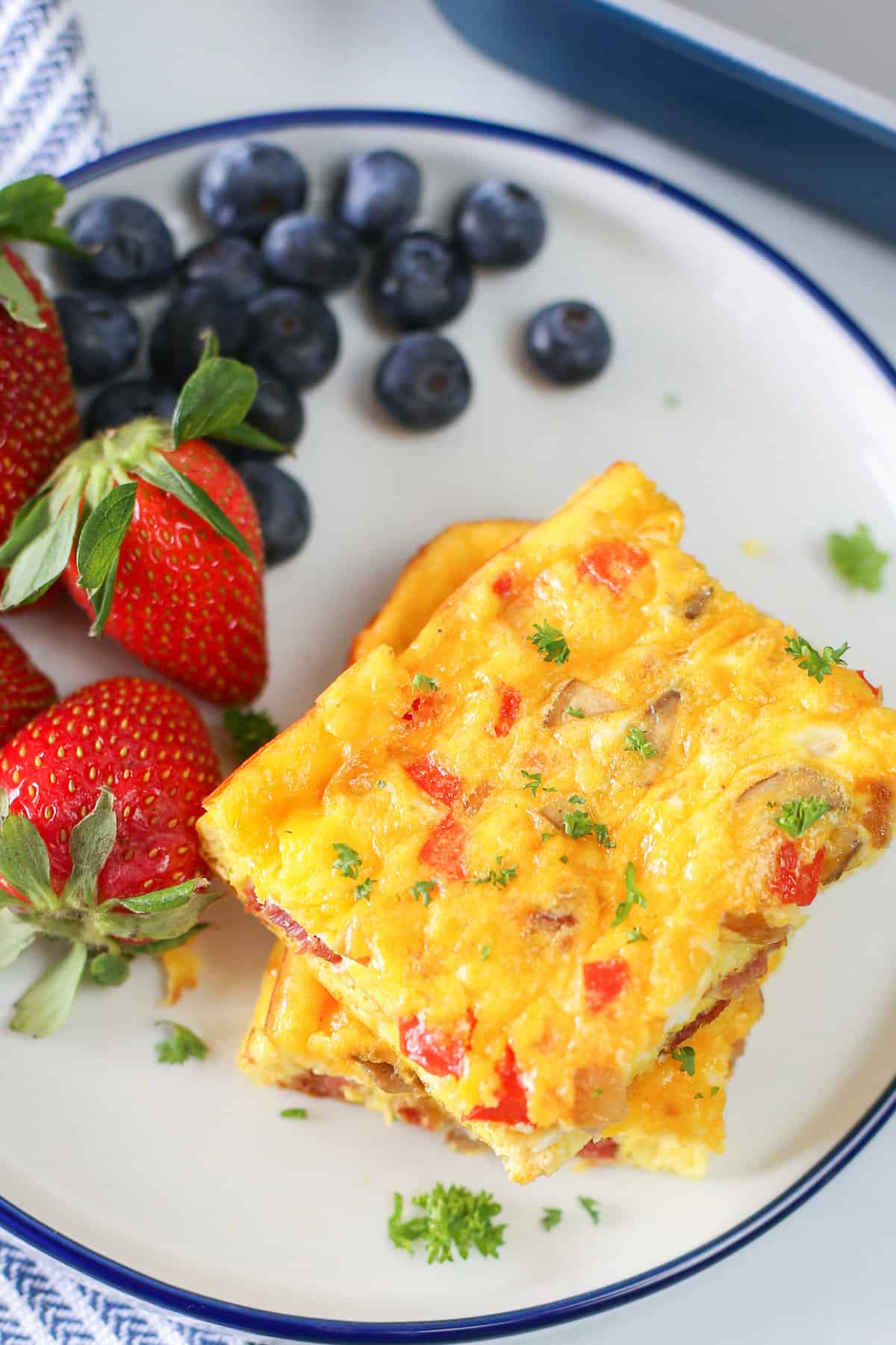 Baked Omelette slice on a plate with strawberries and blueberries.