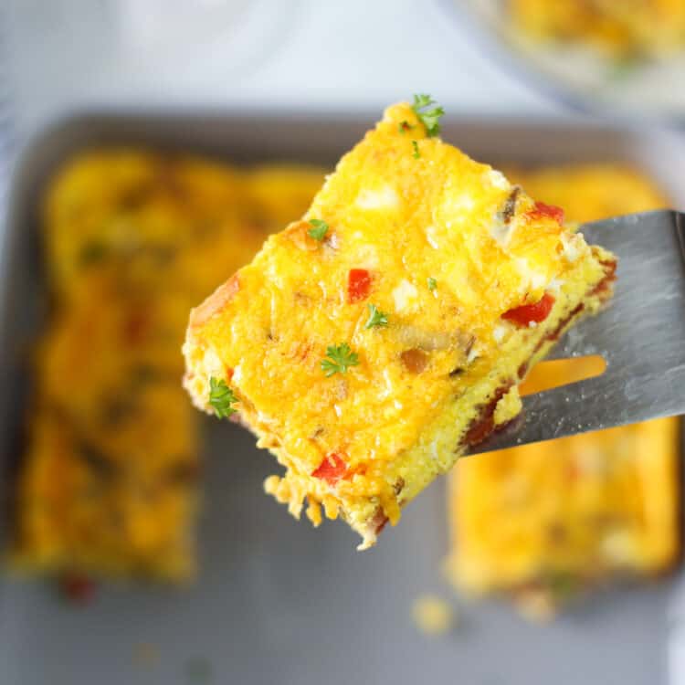 Spatula lifting a slice of baked omelette up out of the pan.