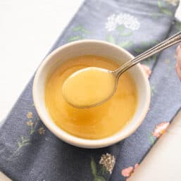 Homemade pineapple sauce in a bowl with a spoon lifting some out.