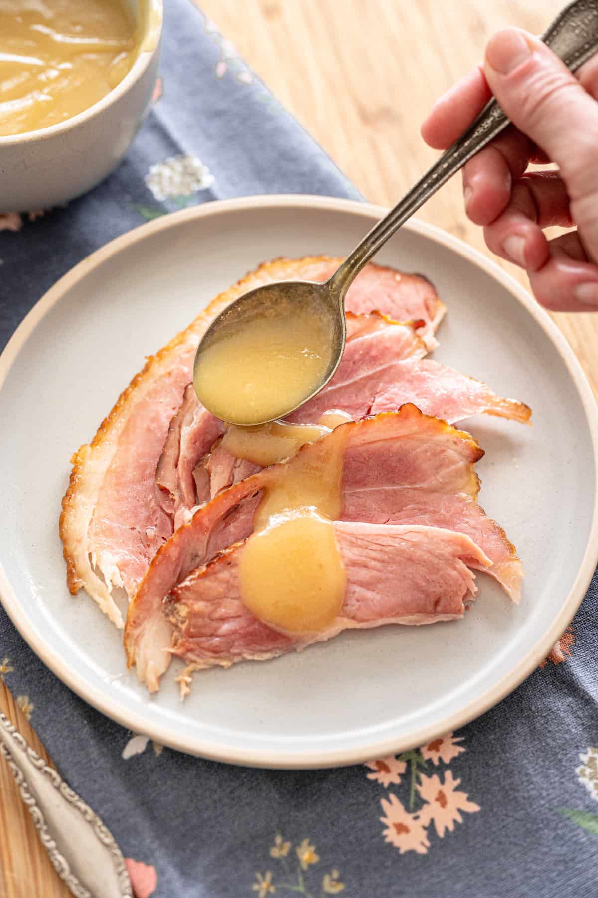Spiral sliced ham with pineapple sauce drizzled over it on a plate.