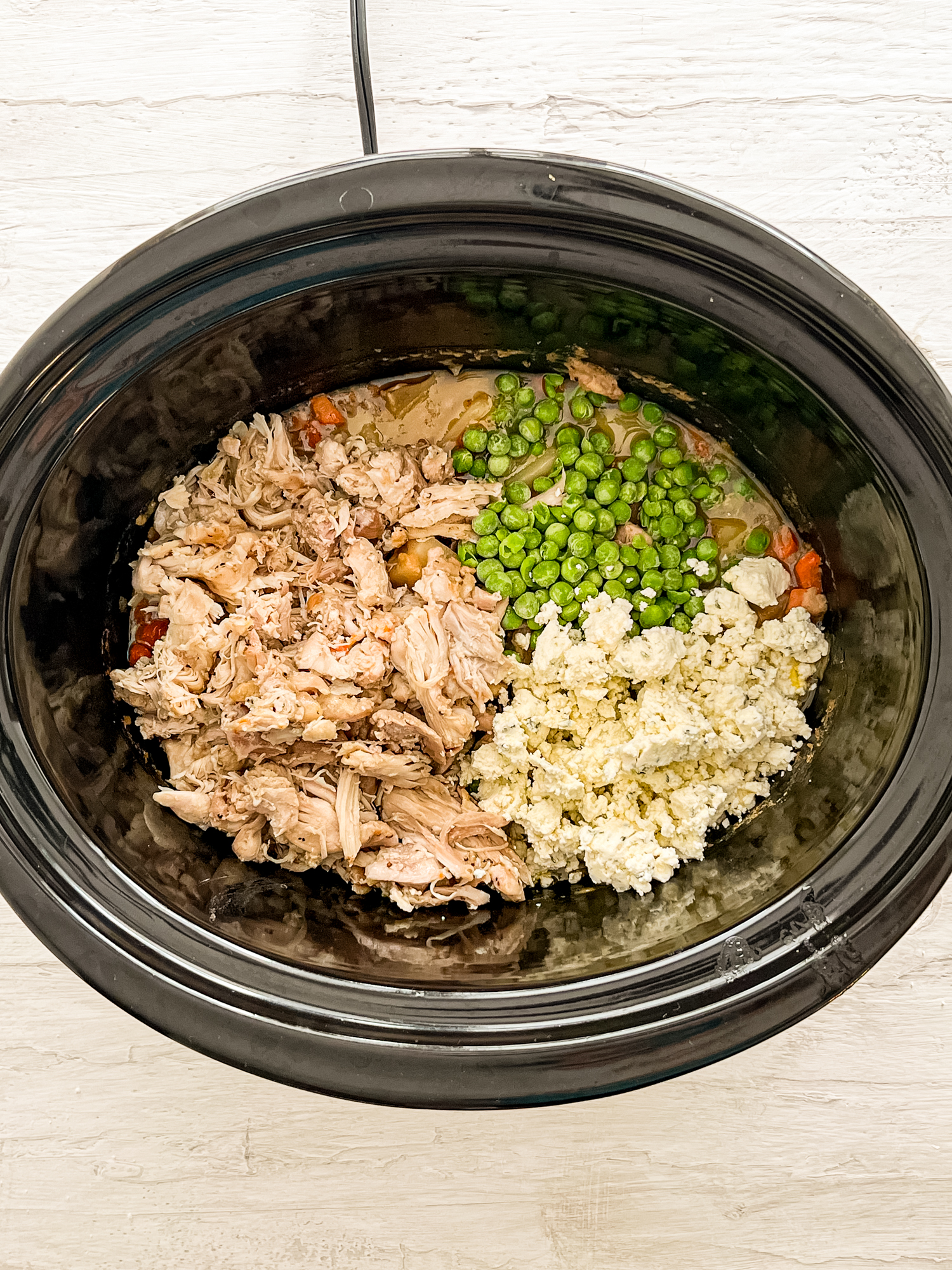 Shredded chicken, crumbled Boursin cheese, sauteed veggies, and frozen peas in a slow cooker.