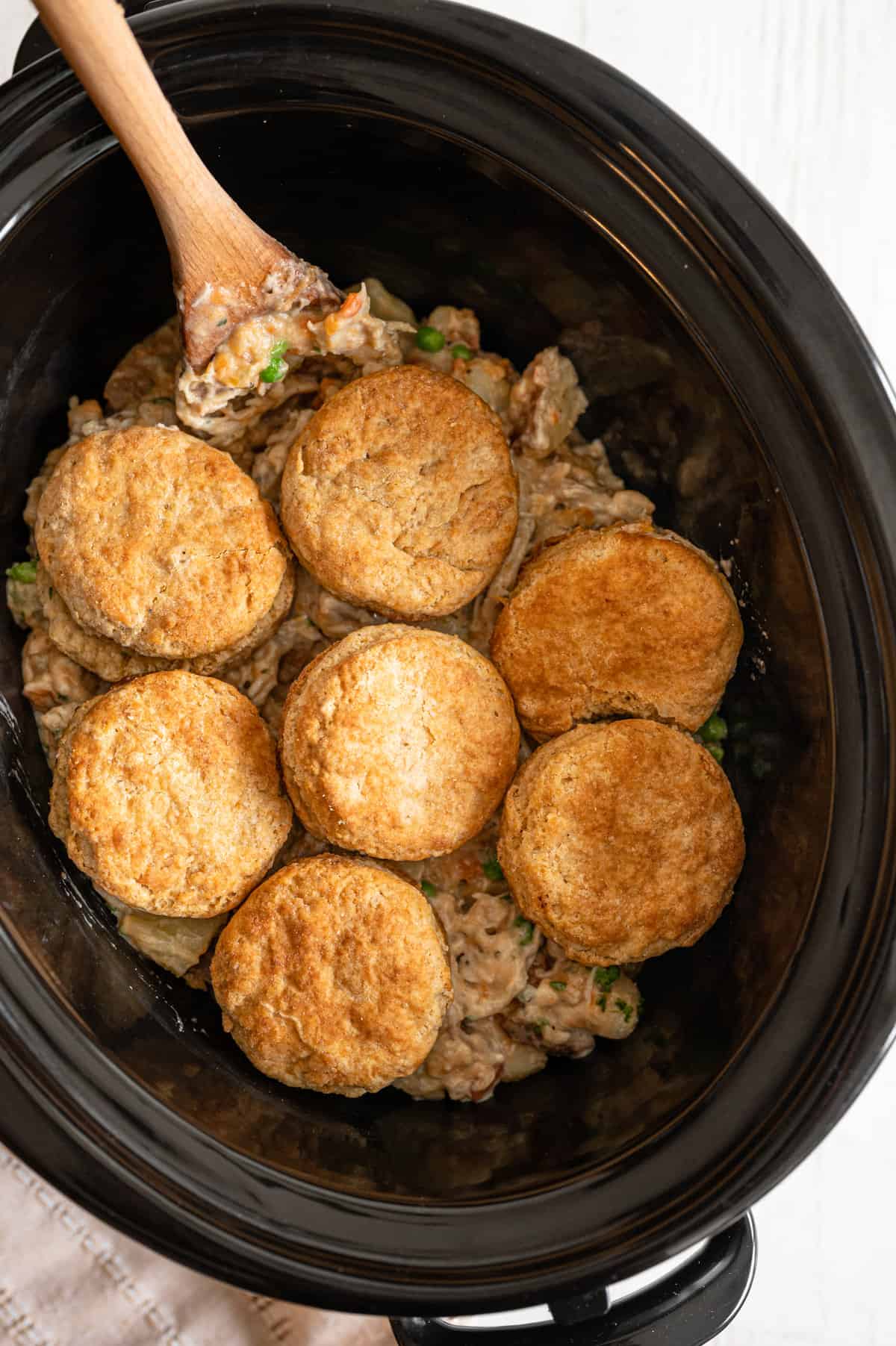 Chicken pot pie mixture in a crock pot with biscuits on top.