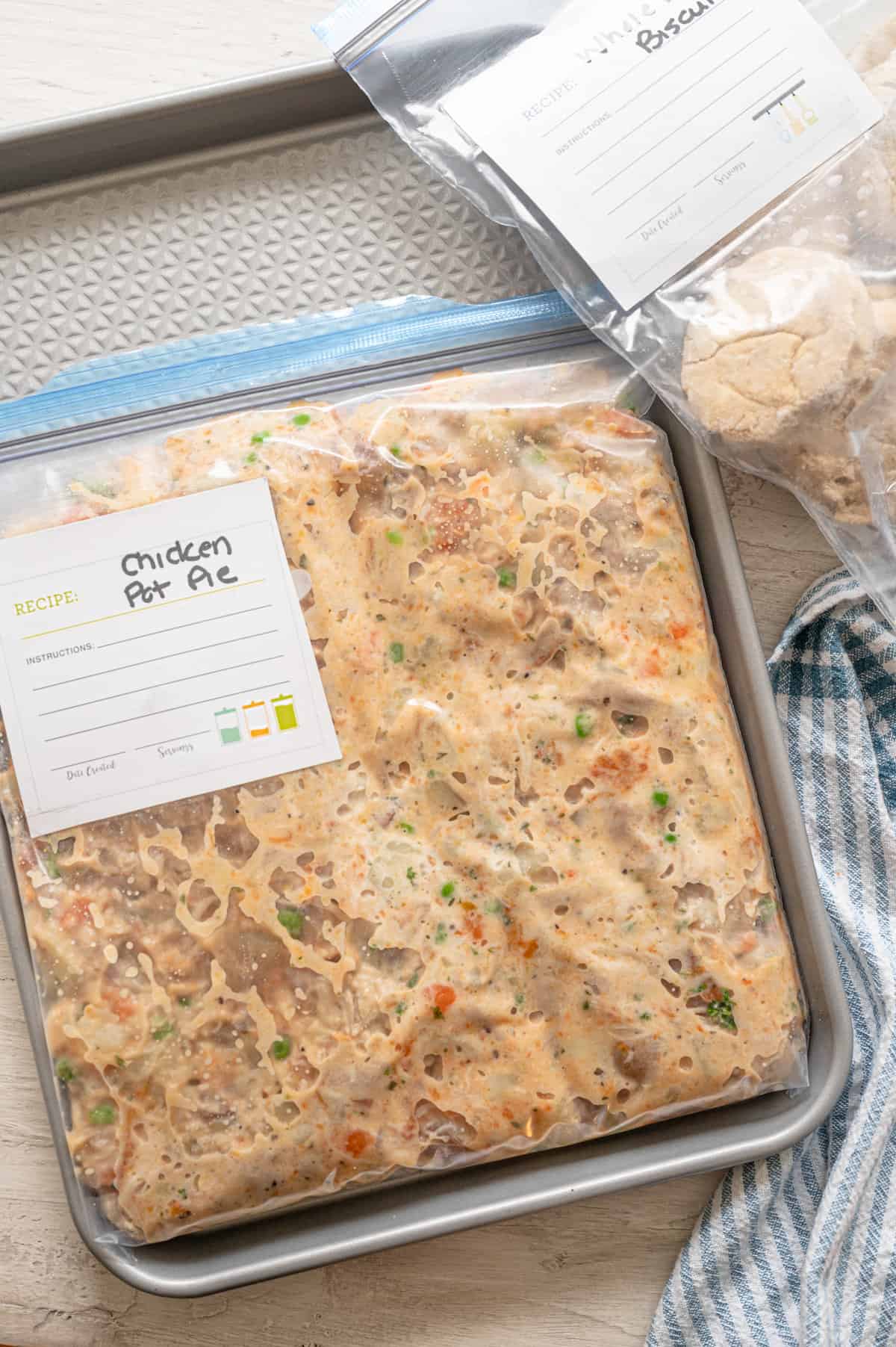 Crockpot chicken pot pie in a freezer meal bag with another bag of frozen biscuits.