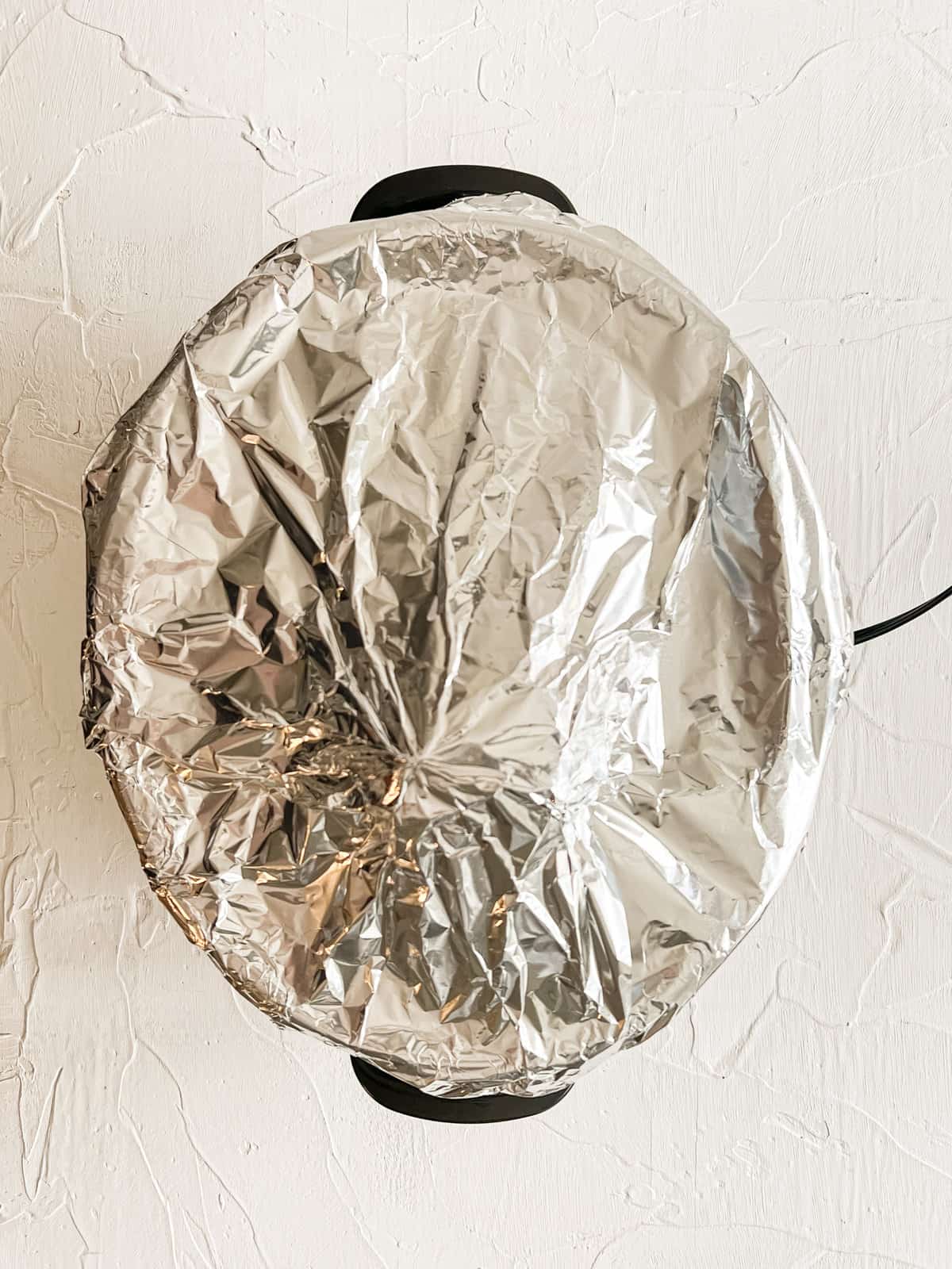 Foil covering a large ham in a slow cooker.