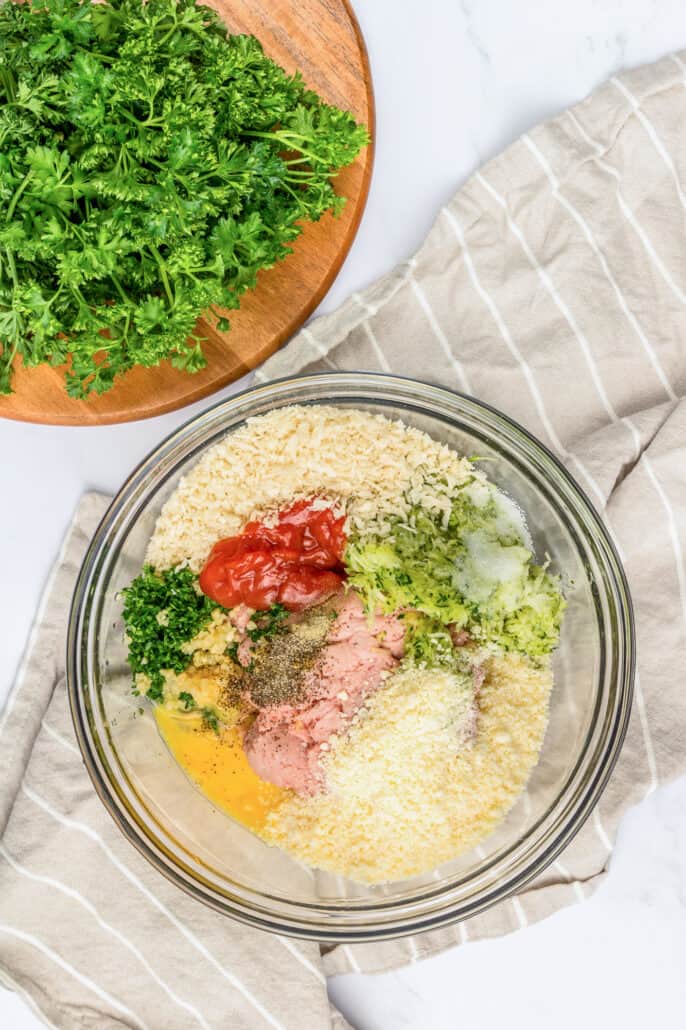 Mixing baked turkey meatball ingredients together in a glass bowl